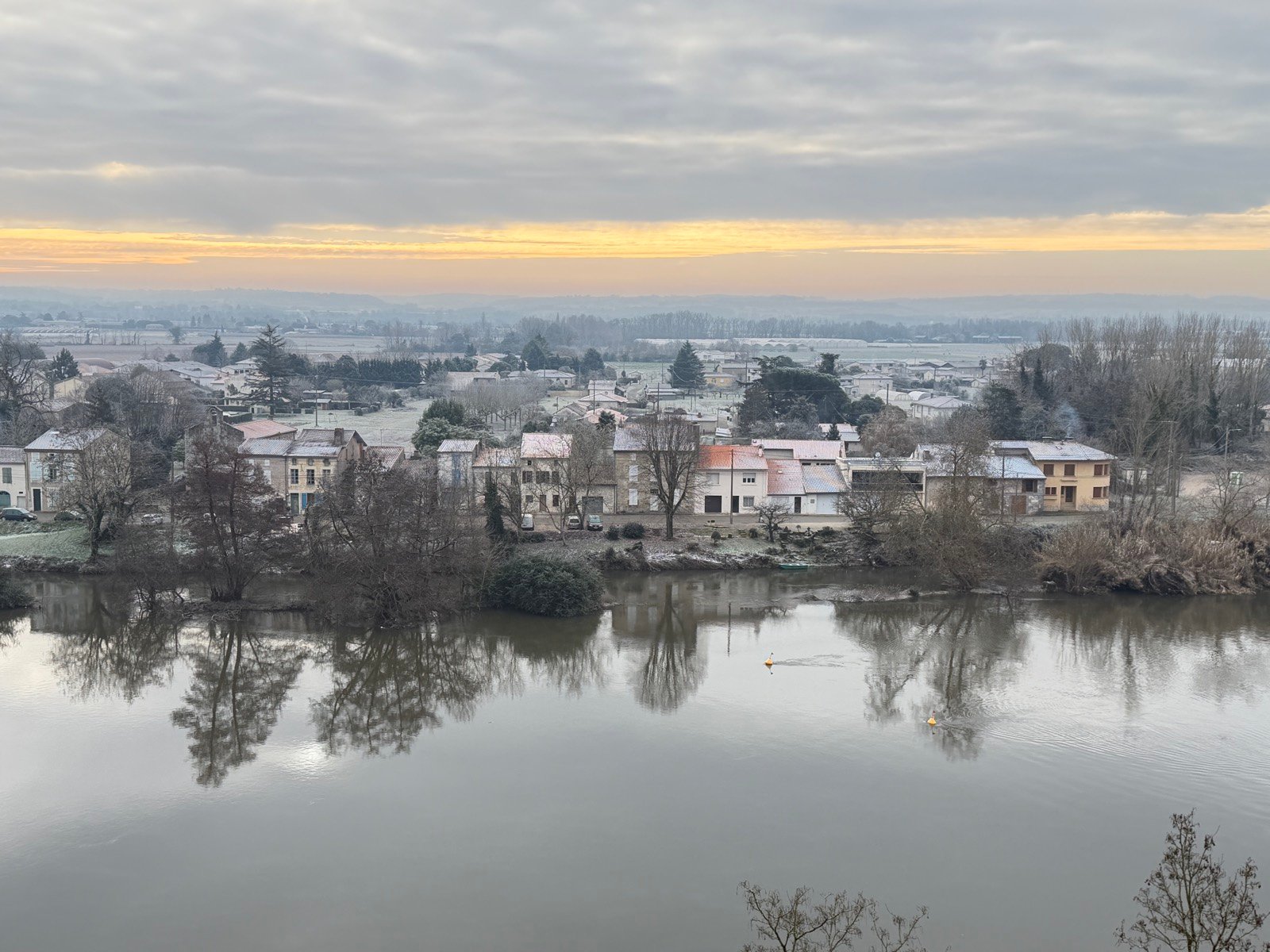Le village entier déroulé sur sa butte, la rivière à ses pieds, le ciel prêt à couvrir.